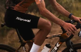 Un ciclista que canaliza el espíritu de States of Elevation - Kilian Jornet, con casco, gafas de sol y ropa de ciclista, monta en una bicicleta Trek por un camino de tierra al aire libre.
