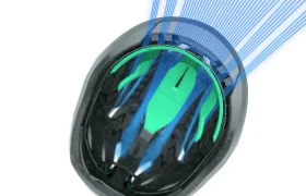 Casco de bicicleta Casco Lazer Sphere KinetiCore negro y verde con líneas azules que ilustran digitalmente el flujo de aire sobre su superficie sobre fondo blanco.