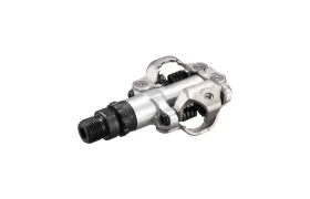 Un pedal de clipless Shimano DEORE XT SPD XC Gravel, con mecanismo de resorte y eje roscado, fotografiado sobre un fondo blanco.