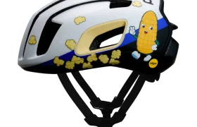Casco de bicicleta blanco y negro decorado con imágenes de palomitas y un personaje animado de maíz sonriente, visto de perfil.