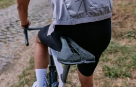 Un ciclista con chaqueta ligera y pantalón corto negro conduce una bicicleta con un moderno sillín PRO Stealth 3D por un camino empedrado.