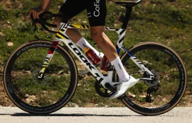 Un ciclista circula en una bicicleta de carretera LOOK 795 Blade RS 3, con un cuadro de diseño colorido, y lleva zapatillas y calcetines blancos, por un camino al aire libre bañado por el sol cerca de Nevers.