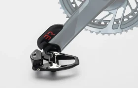Juego de pedales y bielas para bicicleta que incorpora un sistema de pedales automáticos con un elegante diseño de potenciómetro sobre un fondo liso.