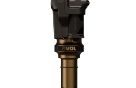 Un primer plano de un amortiguador trasero FOX para bicicleta de montaña con un acabado negro y dorado, diales de ajuste y etiquetado "EVOL" cerca de la base destaca el diseño premium X Factor visto en los amortiguadores FOX.