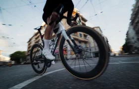 Un ciclista con zapatillas blancas circula en una bicicleta de carretera LOOK 795 Blade RS 3 por una calle de Nevers, con edificios y cables aéreos visibles al fondo.