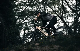 Una persona con casco y equipo de protección conduce una Fantic Sierra e-MTB por un sendero boscoso.