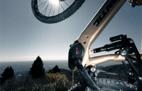 Primer plano del cuadro de una Fantic Sierra e-MTB y el motor Bosch CX Gen5, con la rueda trasera levantada y la luz del sol brillando a través de la rueda sobre un pintoresco telón de fondo al aire libre.
