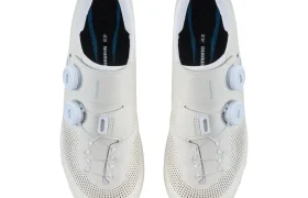 Un par de zapatillas de ciclismo blancas de Shimano con cierre de doble dial, parte superior perforada y plantillas negras, vistas desde arriba: perfectas para aventuras de gravel y repletas de tecnología de competición.