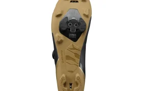 La parte inferior de unas zapatillas de ciclismo Shimano RX710 con suela de color beige, cala negra acoplada y dibujo de la suela visible. Las palabras «Shimano» y «Carbon» aparecen impresas en la suela, lo que destaca su tecnología de competición, ideal para rutas de grava.