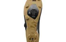 La imagen muestra la suela de color beige y negro de unas zapatillas de ciclismo Shimano RX710 con puntos de fijación para calas sobre un fondo blanco, lo que pone de relieve una tecnología de competición ideal para las zapatillas de gravel.