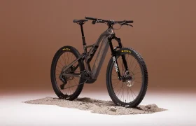 Una Fantic Sierra e-MTB con neumáticos gruesos y suspensión total, propulsada por un motor Bosch CX Gen5, se alza sobre un trozo de tierra sobre un fondo marrón liso.