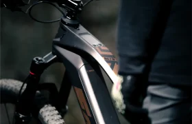 Primer plano del cuadro y la zona del manillar de una Fantic Sierra e-MTB con pantalla digital, que incorpora el motor Bosch CX Gen5, junto a una persona vestida con ropa oscura.