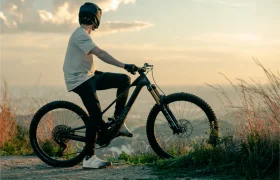 Una persona con casco se sienta en una bicicleta de montaña UNNO MITH, contemplando un paisaje pintoresco al atardecer.