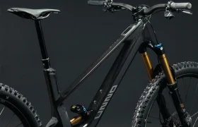 La UNNO MITH es una elegante bicicleta de montaña negra con un cuadro resistente, neumáticos con tacos y suspensión delantera, que se presenta perfectamente sobre un fondo oscuro y liso.