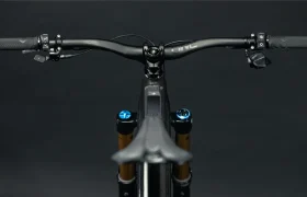 Primer plano de un manillar de bicicleta UNNO MITH sobre un fondo oscuro, que muestra sus empuñaduras, palancas de freno y cambios de precisión.
