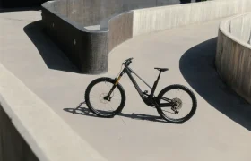 La bicicleta de montaña UNNO MITH descansa elegantemente sobre un camino de hormigón curvo, flanqueado por imponentes paredes en un rincón rodeado de sombras.