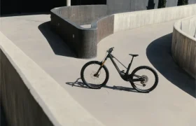 Una bicicleta de montaña UNNO MITH está estacionada sobre una superficie de concreto, rodeada de paredes curvas en un entorno urbano, proyectando una elegante sombra en el suelo.