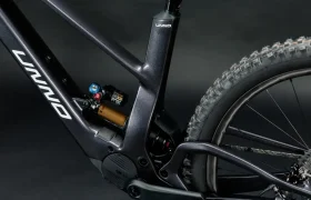 Primer plano de un cuadro de bicicleta UNNO MITH negro que resalta la rueda trasera y el sistema de suspensión, sobre un fondo oscuro.