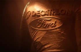 Logotipos de Decathlon y Ford grabados en relieve sobre una superficie texturizada de color arcilla.