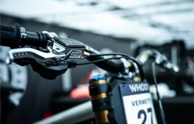 Primer plano del manillar de una bicicleta de montaña con la palanca de freno TRP EVO PRO Anniversary Edition, la placa con el número «27» y un fondo desenfocado, que captura la emoción de una edición limitada que recorre la Península Ibérica.