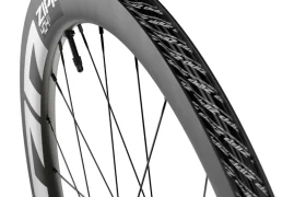 Primer plano de una rueda de bicicleta de carbono Zipp 404 S en el que se aprecian la llanta, los radios y el dibujo de la banda de rodadura de la marca, famosa por su velocidad.