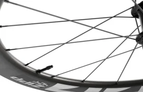 Primer plano de una rueda de bicicleta de carbono Zipp 404 S en el que se aprecian los radios, la válvula y el logotipo de la llanta sobre un fondo blanco, diseñada para ofrecer la máxima velocidad y rendimiento. Descubre más sobre su competitivo precio.
