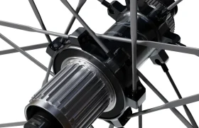 Primer plano del buje de una rueda de bicicleta con radios metálicos, en el que se aprecian con detalle los componentes y las piezas mecánicas de la serie Shimano Dura-Ace WH-R9370. La imagen destaca la ingeniería de precisión y el diseño avanzado característicos de las ruedas de carbono para el ciclismo de alto rendimiento.