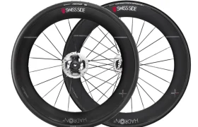 Dos ruedas de bicicleta aerodinámicas negras con llantas de carbono profundas etiquetadas "Swiss Side" y "HADRON³ Ultimate 650", una de ellas con rotor de freno de disco. Aprobadas por la UCI y diseñadas para una aerodinámica superior, colocadas en posición vertical y superpuestas.