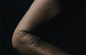 Primer plano de una rodilla doblada con medias de rejilla texturizadas, en las que se aprecian el estiramiento y los pliegues del tejido sobre un fondo oscuro, lo que recuerda a la elegancia ajustada propia de prendas de manga larga como el Corretto LS Jersey o el Castelli Transition.