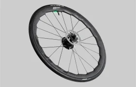 Se muestra una rueda de bicicleta Zipp 2026 negra con rotor de freno de disco, radios y neumático sin cámara sobre un fondo gris simple, diseñada para ayudarte a rodar más rápido en cada recorrido.