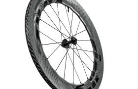 Una rueda de bicicleta de fibra de carbono Zipp 2026 con llantas aerodinámicas de sección profunda y radios negros, diseñada para rodar más rápido, mostrada sobre un fondo blanco.