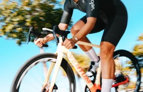 Una persona que lleva casco y equipación de ciclismo monta en una bicicleta de carretera con ruedas Zipp 404 S al aire libre en un día soleado; la velocidad es evidente al ver cómo los árboles y el cielo pasan borrosos por el fondo.