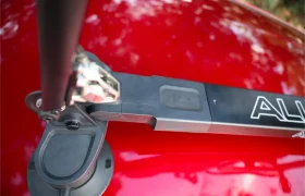 Primer plano de un portabicicletas Allen Smart Suction montado en el techo de un coche rojo brillante, en el que destaca el robusto mecanismo del portabicicletas y los pedales.