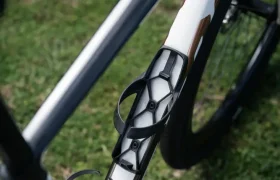 Primer plano de un cuadro de bicicleta BMC Kaius 01 con dos portabidones vacíos montados en el tubo diagonal, colocado sobre hierba, que muestra la esencia de una bicicleta rápida.