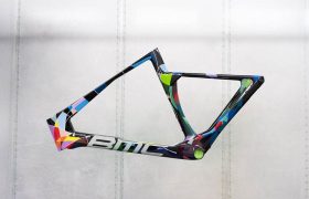 Un cuadro de bicicleta BMC VAR0 con un patrón geométrico colorido, mostrado sobre un fondo blanco liso.