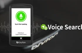 La pantalla del smartphone muestra el mensaje de búsqueda por voz "Toca para empezar a hablar" junto a un icono de micrófono verde. Al fondo, el texto en negrita indica "Búsqueda por voz" con gráficos dinámicos de ondas sonoras, que evocan la conectividad fluida que ofrecen dispositivos como el Bryton Rider S810.