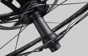 Vista de cerca de un cubo de rueda de bicicleta Zipp 2026 con rotor de freno de disco y radios acoplados, fotografiado sobre un fondo gris simple, diseñado para rodar más rápido.