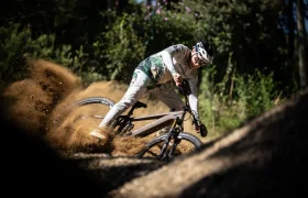 Un ciclista de montaña derrapa en una curva de tierra, levantando polvo, mientras recorre una pista forestal a la luz del día, como los momentos llenos de adrenalina que describe en una entrevista Jordi Bagó.