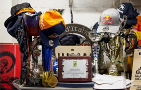 Una exhibición de trofeos, medallas, placas y gorras -incluida una gorra de Red Bull- dispuesta en una estantería con diversos recuerdos y artículos de carreras de la Entrevista a Josep García.