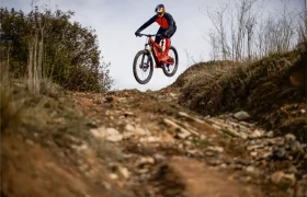 Un ciclista con equipo de protección monta en bicicleta de montaña por un sendero de tierra rocosa y salta por encima de una elevación, como en las escenas descritas en una entrevista a Josep García.