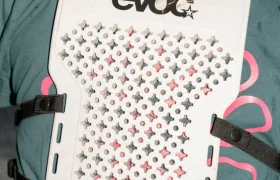 Persona que lleva un EVOC Torso Protector blanco con diseño perforado y correas de sujeción sobre una camiseta verde, aquí en talla XS.