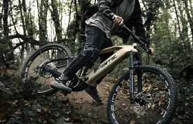 Con casco y gafas de sol, un ciclista atraviesa un frondoso sendero forestal en una Fantic Sierra e-MTB, inclinándose con confianza en la curva mientras el motor Bosch CX Gen5 impulsa su descenso.