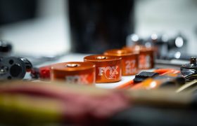 Primer plano de llaves de vaso naranjas de la marca Fox y herramientas variadas sobre un banco de trabajo, con el fondo desenfocado.