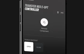 La pantalla de un smartphone muestra la interfaz de una aplicación para gestionar un controlador FOX Transfer Neo E-Opt, que incluye opciones para retirar un componente y activar o desactivar la tija de sillín electrónica, además de información sobre el firmware e-Optimized y la versión de la aplicación.