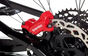 Primer plano de una pinza de freno de disco hidráulico Brembo GR-PRO roja montada en una e-MTB, mostrando el rotor de freno y parte del cuadro de la bicicleta: frenos ideales para los entusiastas de la gravedad.