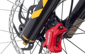 Primer plano de un sistema de freno de disco delantero e-MTB con pinza Brembo GR-PRO roja y horquilla negra con detalles amarillos, que pone de relieve las prestaciones de gravedad de los frenos de alto nivel.