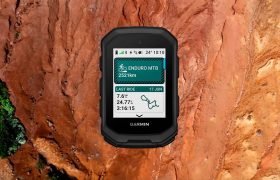Un ciclocomputador Garmin Edge MTB muestra los datos de la bicicleta de montaña -distancia, fecha, tiempo de recorrido y un mapa de ruta- sobre un fondo de terreno rocoso rojizo.