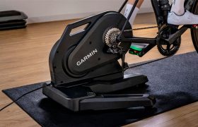 Un rodillo inteligente para bicicleta de Garmin sobre una alfombra, con una bicicleta acoplada.