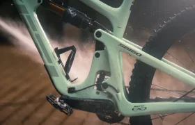Una bicicleta de montaña de color verde claro a la que le están echando agua con una manguera.