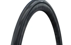 Primer plano de una cubierta de bicicleta Schwalbe Pro One negra colocada en posición vertical sobre un fondo blanco, en el que se aprecian el dibujo de la banda de rodadura y la textura del flanco de la rueda trasera.